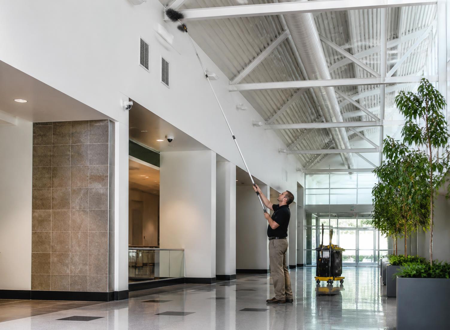 Technician performing high dusting in a commercial atrium